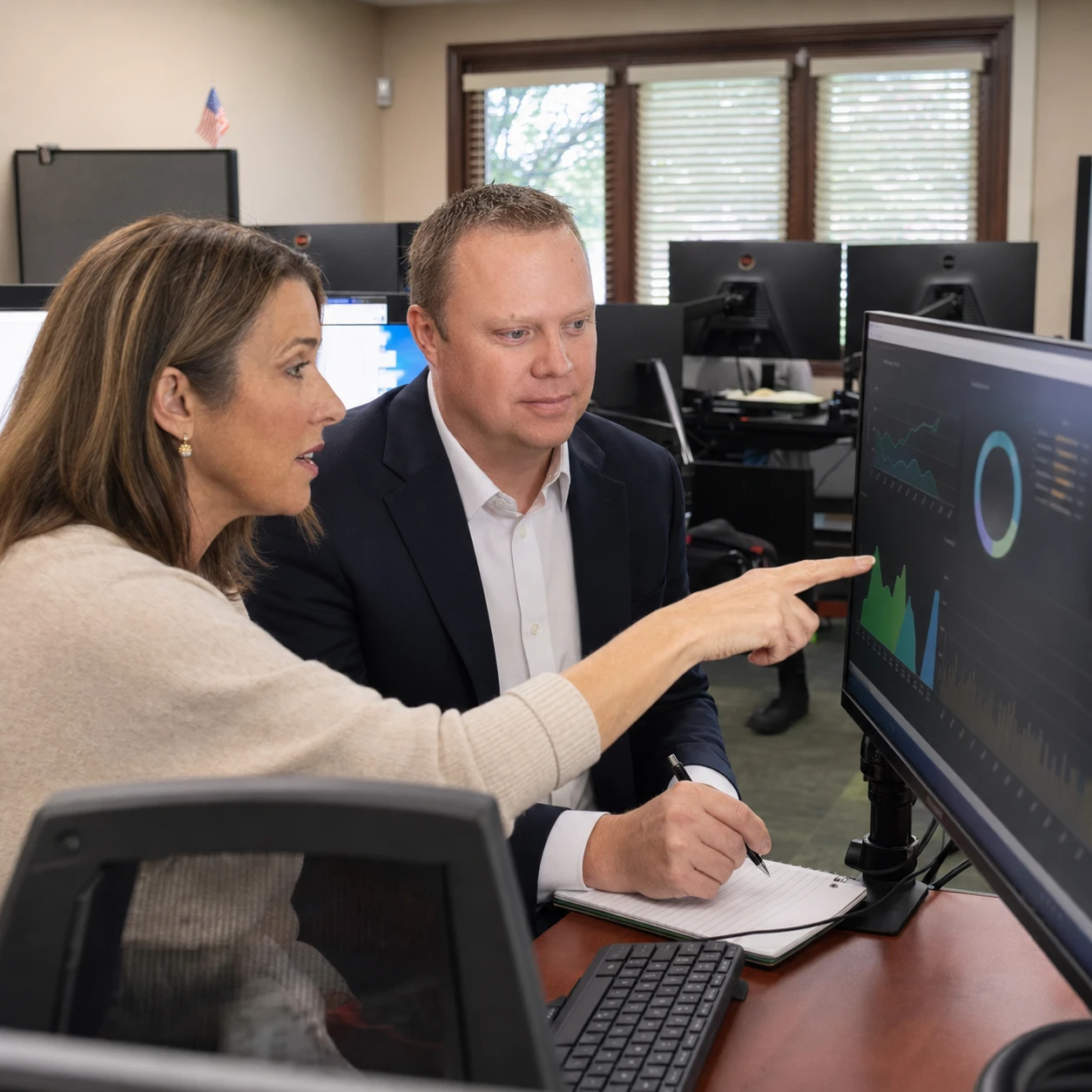 A Cooper Norman advisor and client review financial dashboards on screen.